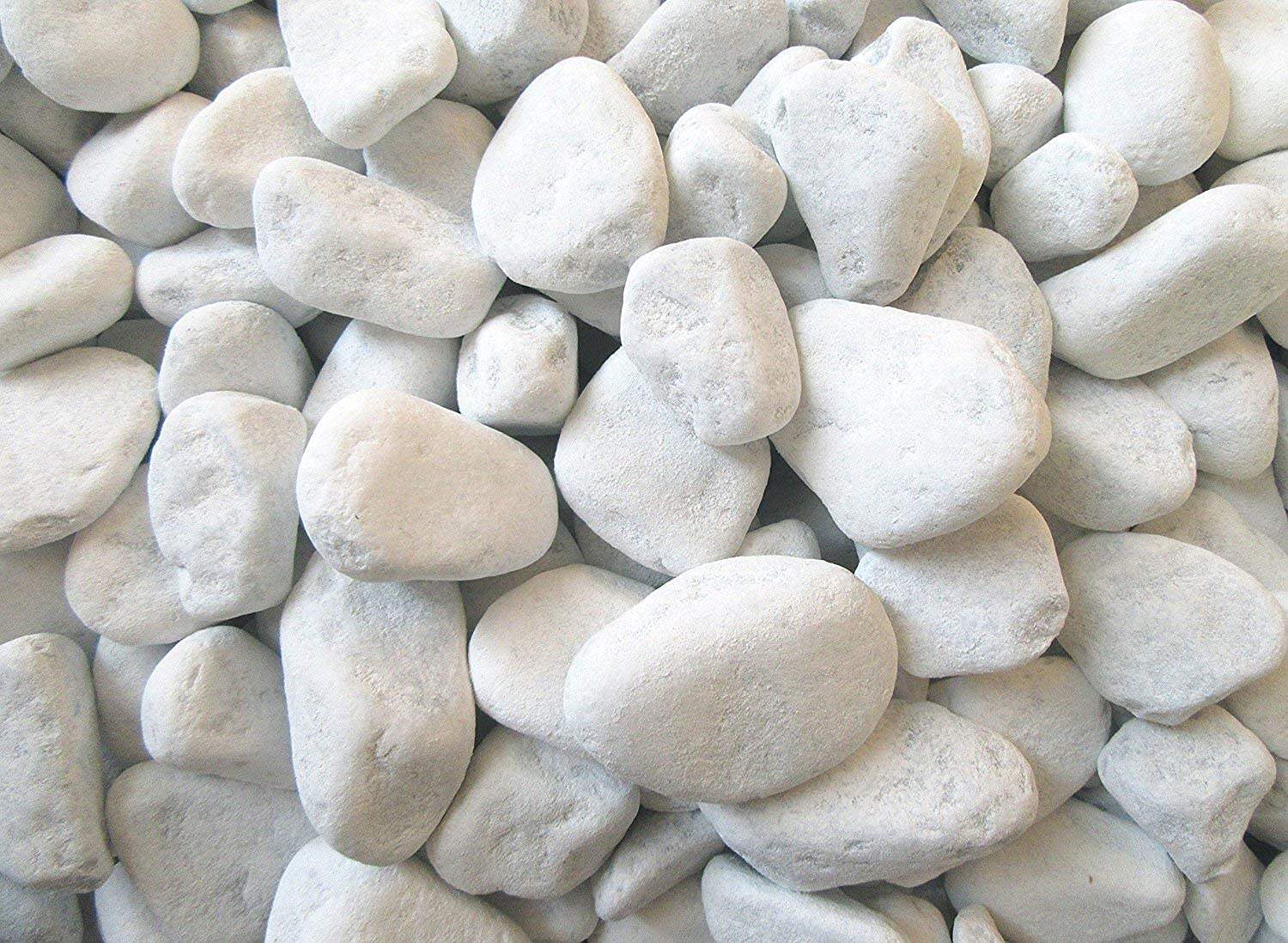 “Ciottoli di marmo Bianco Carrara 25–40 mm disposti in natura, illuminati dalla luce solare con ombre morbide.”